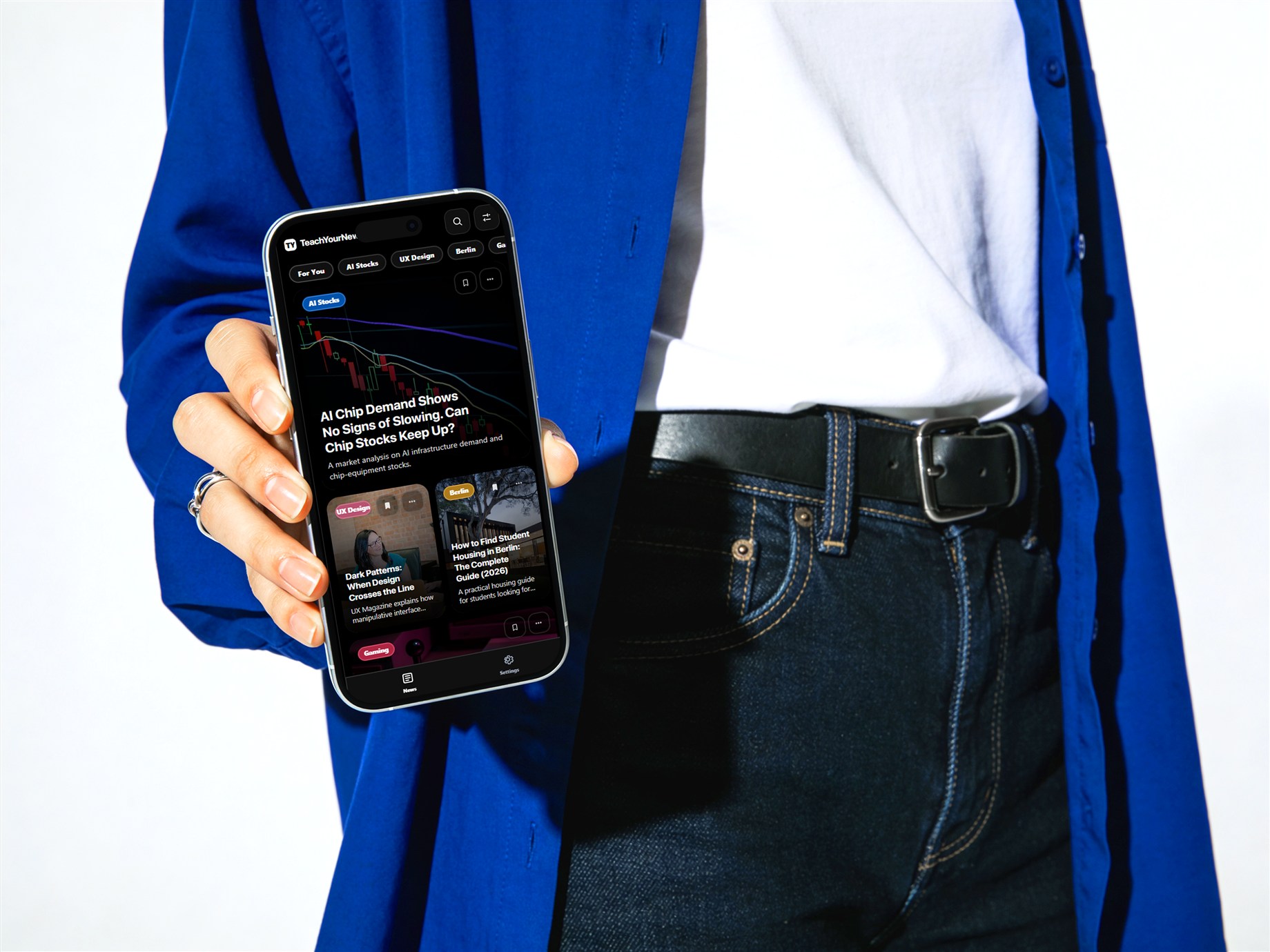 Person in a blue jacket holding the Teachable Newsfeed mobile prototype
