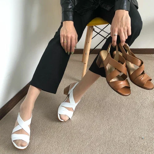 Styled product photograph showing white and brown women's sandals
